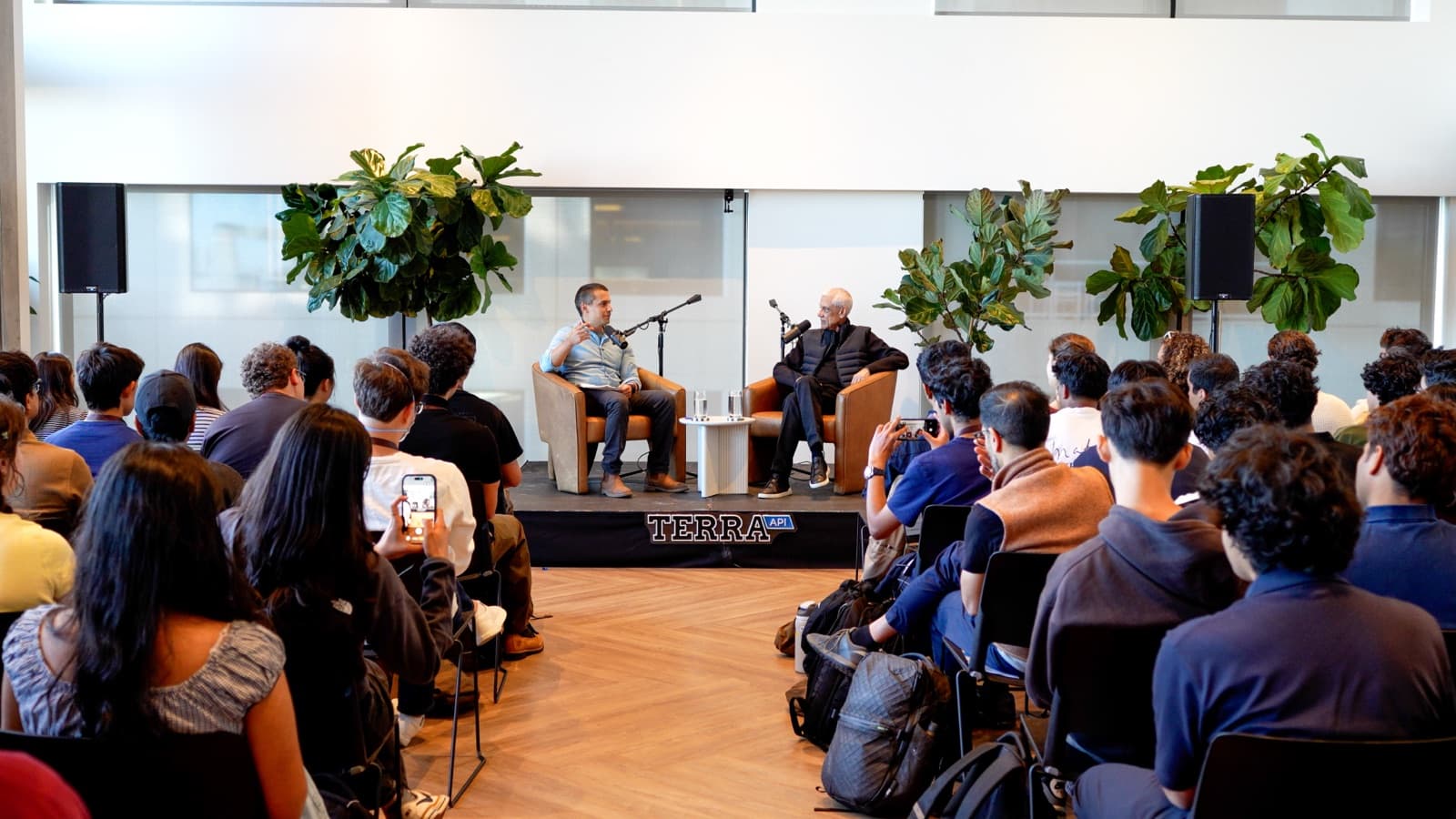 A live Iron Foundry recording: the host and a guest in armchairs on a Terra API stage, in front of a seated audience